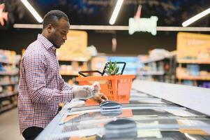 African man shopping at supermarket. Handsome guy holding shopping basket photo