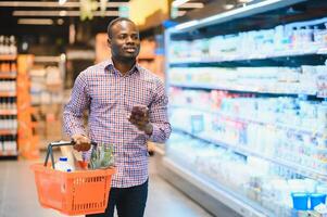 African man shopping at supermarket. Handsome guy holding shopping basket photo