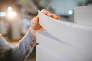 Man working in printing house with paper and paints photo