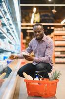 African man shopping at supermarket. Handsome guy holding shopping basket photo