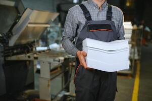 Man working in printing house with paper and paints photo