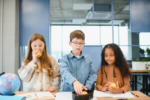 multirracial Niños de escuela teniendo almuerzo a el escritorio durante un descanso en colegio foto