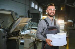 Man working in printing house with paper and paints photo