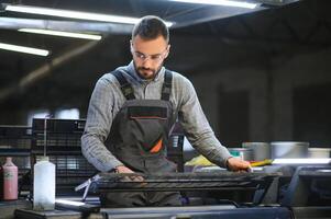 Man working in printing house with paper and paints photo