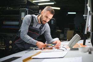 Graphic engineer or worker checking imprint quality in modern print shop photo