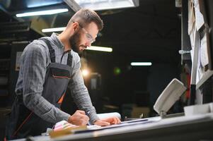 Print house worker controlling printing process quality and checking colors with magnifying glass photo