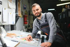 Man working in printing house with paper and paints photo