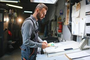 Print house worker controlling printing process quality and checking colors with magnifying glass photo