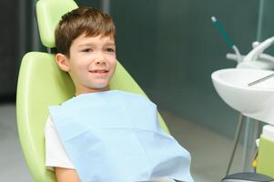 sorprendido pequeño chico sentado en el del dentista silla foto