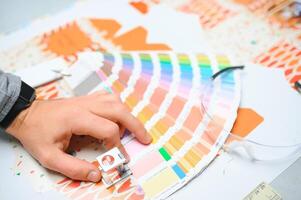 Man working in printing house with paper and paints photo