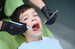 Dentist examining little boy's teeth in clinic photo