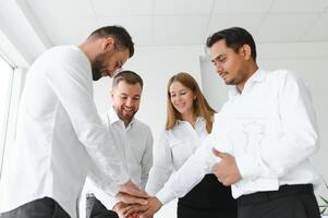 Happy successful multiracial business team giving a high fives gesture as they laugh and cheer their success. photo