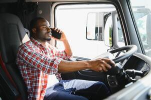 africano conductor en el cabina de un camión hablando en el teléfono. foto