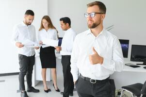 Team leader stands with coworkers in background photo