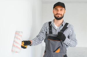 Young professional worker in uniform standing with paint roller. photo