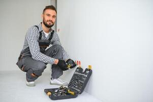 Electrician Builder at work, installation of sockets and switches. Professional in overalls with an electrician's tool. Against the background of the repair site photo