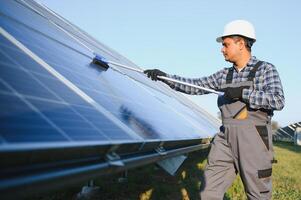 Indian handyman cleaning solar panels form dust and dirt photo