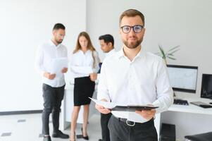 Team leader stands with coworkers in background photo