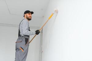 joven trabajador pintura pared en habitación. foto