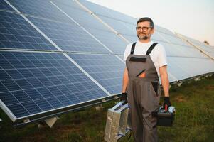 Portrait of senior worker in uniform standing near solar panels photo