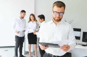 Team leader stands with coworkers in background photo