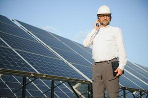 Solar power plant. Man standing near solar panels. Renewable energy photo