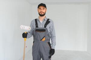 joven profesional trabajador en uniforme en pie con pintar rodillo. foto