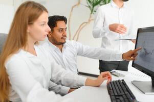 Business professionals. Group of young confident business people analyzing data using computer while spending time in the office photo