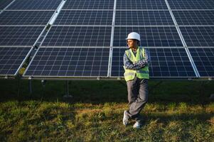 indio hombre en uniforme en solar granja. competente energía ingeniero controlador trabajo de fotovoltaica células foto