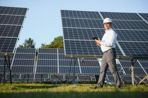 solar poder planta. hombre en pie cerca solar paneles renovable energía foto