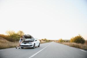 hermosa sexy mujer cerca un roto coche. confuso mujer lo hace no saber qué a hacer foto