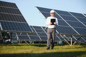 solar poder planta. hombre en pie cerca solar paneles renovable energía foto