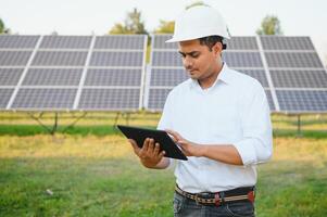 retrato joven indio técnico o gerente vistiendo formal paños en pie con solar panel. renovable energía, hombre en pie cruzado brazo, Copiar espacio foto