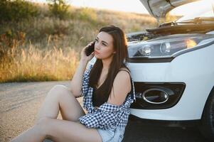 joven sexy mujer con roto coche vocación en el célula teléfono. foto
