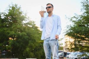 joven ciego hombre con teléfono inteligente en ciudad, vocación foto