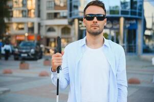 Portrait of a young, handsome blind man walking in the city. The concept of limited physical capabilities. photo
