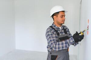 an Indian electrician installs an outlet in a new building photo