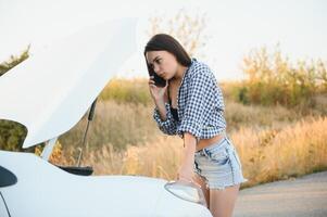 Women talking on the phone about problem with her car she can't. Young sexy girl consults on the phone during car repair photo