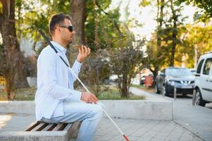 Young blinded man using phone and sending voice message photo