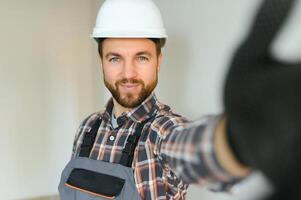 retrato de positivo, hermoso joven masculino constructor mientras trabajando a construcción sitio. foto