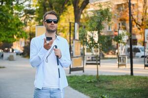 ciego hombre. visualmente dañado hombre con caminando palo, foto