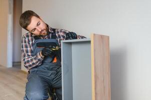 Professional Furniture Assembly Worker Assembles Shelf. Professional Handyman Doing Assembly Job Well photo
