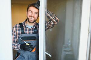 Young repairman adjusting a terrace door handle with screwdriver photo