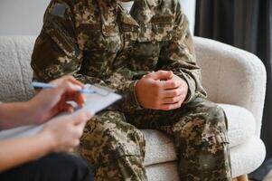 cropped shot of soldier and psychiatrist holding hands during therapy session. photo