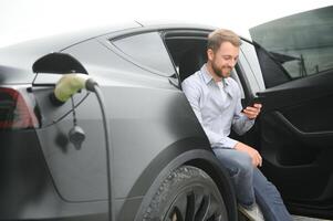 a man charges an electric car photo