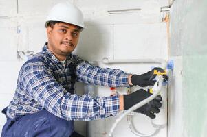 Indian plumber installing water equipment - meter, filter and pressure reducer photo