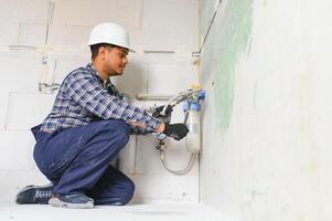 Indian plumber installing water equipment - meter, filter and pressure reducer photo