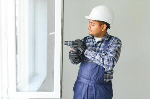 Indian service man installing window with screwdriver photo