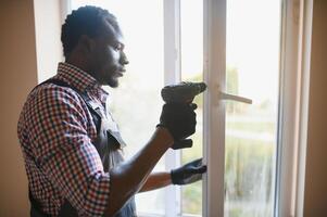 africano personal de mantenimiento reparando roto ventana en balcón foto