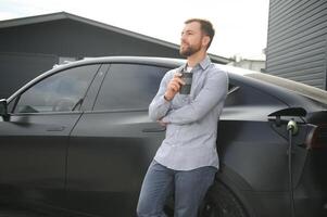 a man charges an electric car photo